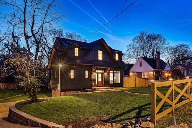 view of front of house featuring fence, a front lawn, and board and batten siding