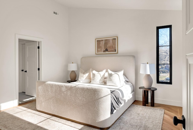 bedroom with visible vents, baseboards, and wood finished floors