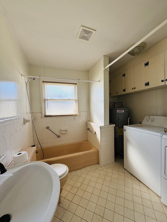 full bathroom featuring sink, separate washer and dryer, water heater, tile patterned floors, and tile walls