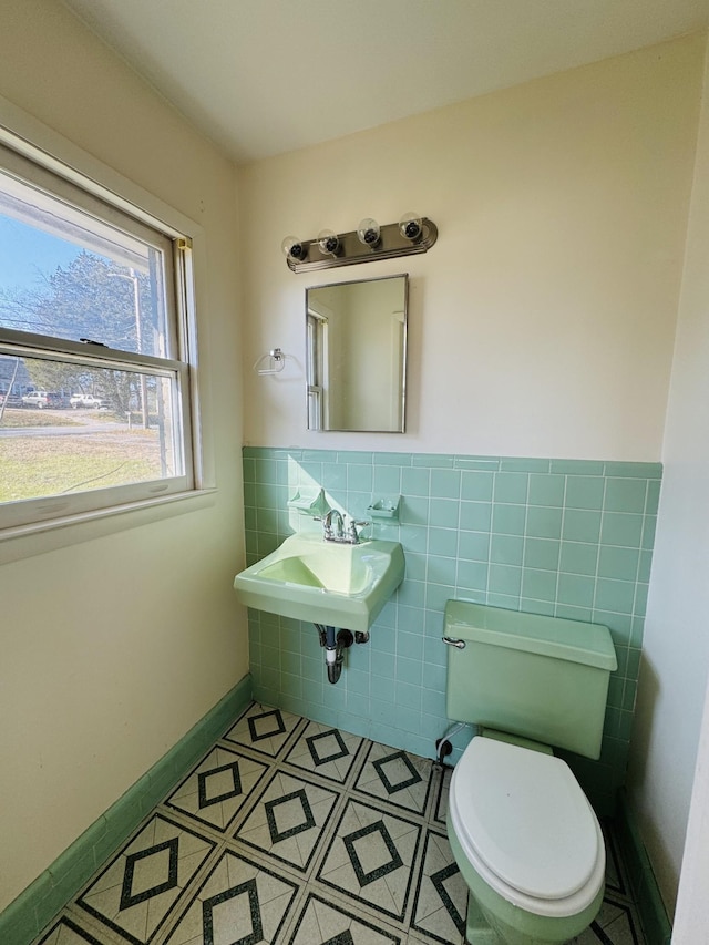 bathroom with tile patterned floors, toilet, sink, and tile walls