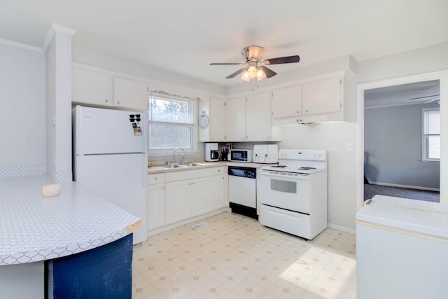 kitchen featuring white cabinetry, sink, a healthy amount of sunlight, and white appliances