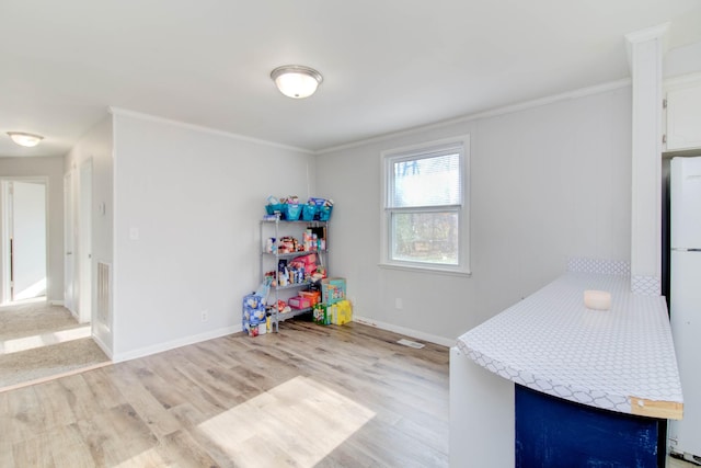 game room with light wood-type flooring and crown molding