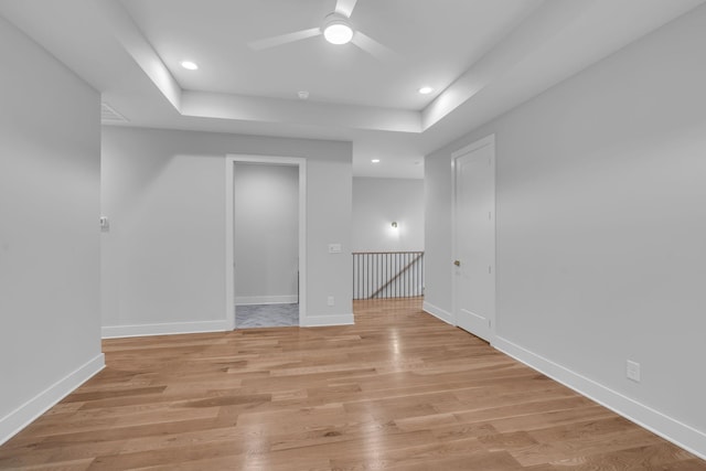 spare room featuring ceiling fan, a raised ceiling, and light wood-type flooring