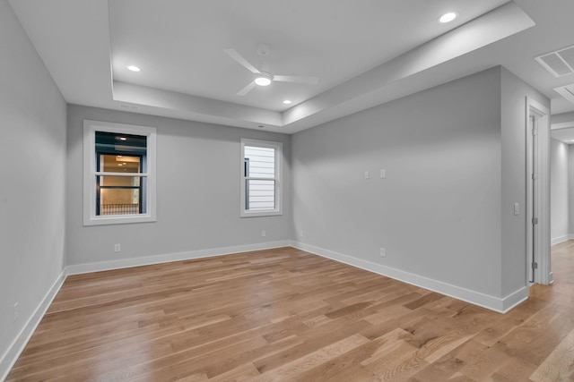 unfurnished room with ceiling fan, a raised ceiling, and light hardwood / wood-style flooring