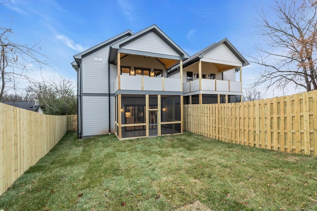 rear view of house featuring a lawn, a sunroom, and a balcony