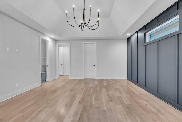 unfurnished dining area featuring light hardwood / wood-style floors, lofted ceiling, and a notable chandelier