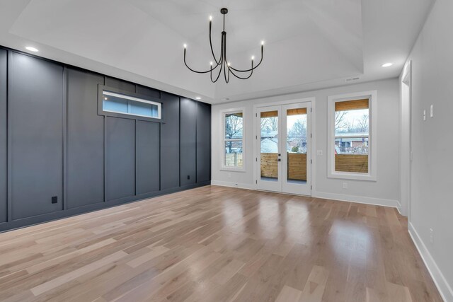 unfurnished room featuring light hardwood / wood-style flooring, a chandelier, and french doors