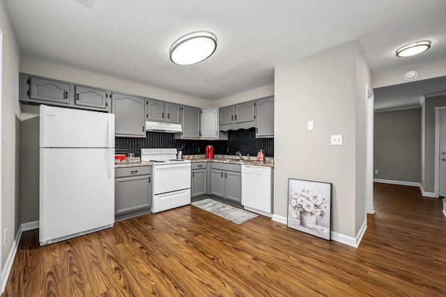 kitchen with tasteful backsplash, gray cabinets, dark hardwood / wood-style floors, and white appliances