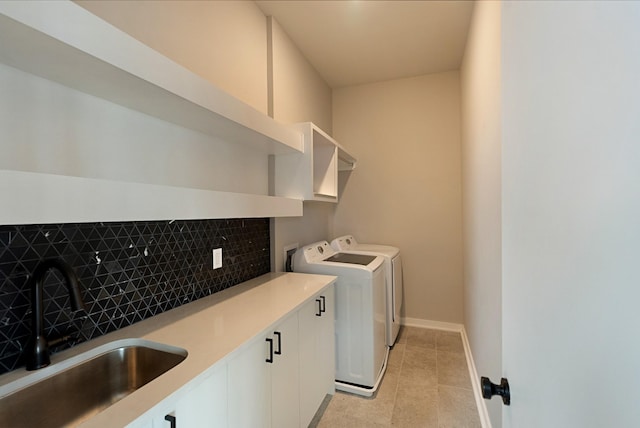 clothes washing area with washer and dryer, light tile patterned flooring, cabinets, and sink