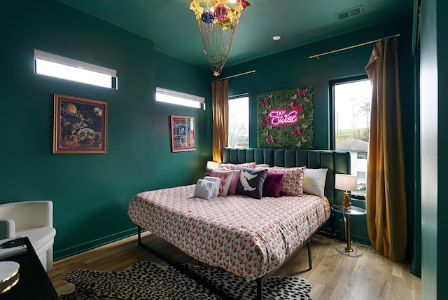 bedroom featuring an inviting chandelier and light wood-type flooring