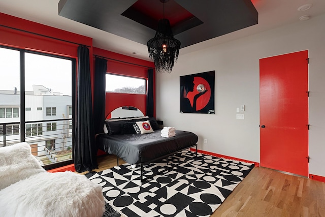 bedroom with light wood-type flooring and a tray ceiling