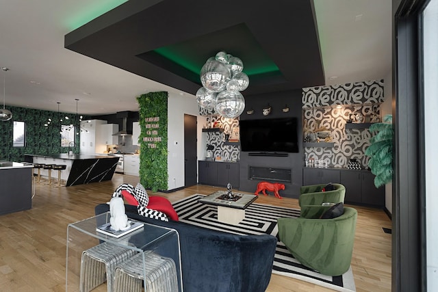 living room featuring light wood-type flooring, a raised ceiling, and sink