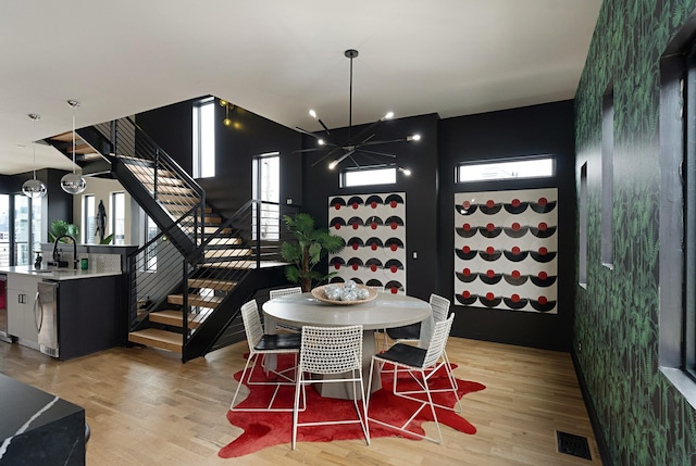 dining space featuring sink, light hardwood / wood-style flooring, a healthy amount of sunlight, and a notable chandelier