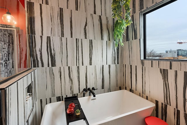 bathroom featuring a washtub and tile walls