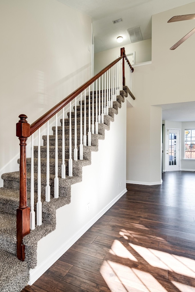 staircase with wood-type flooring and a high ceiling