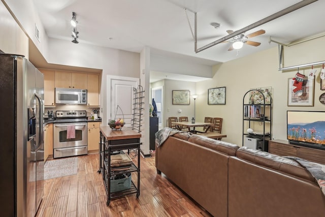 living room featuring ceiling fan, dark hardwood / wood-style flooring, and rail lighting