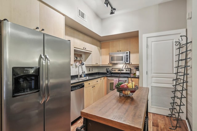 kitchen with light brown cabinetry, wood-type flooring, sink, and appliances with stainless steel finishes