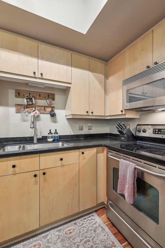 kitchen with light hardwood / wood-style floors, light brown cabinetry, sink, and appliances with stainless steel finishes