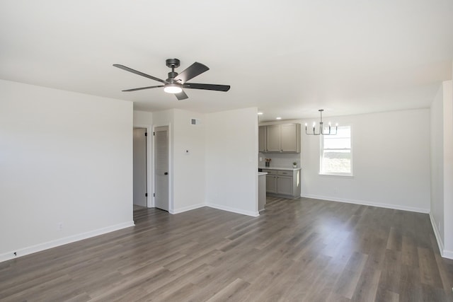 unfurnished living room featuring ceiling fan with notable chandelier and dark hardwood / wood-style floors