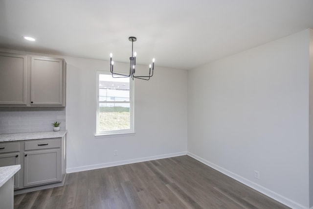 unfurnished dining area with a chandelier and dark hardwood / wood-style flooring