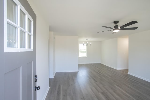 unfurnished room featuring ceiling fan with notable chandelier and dark wood-type flooring