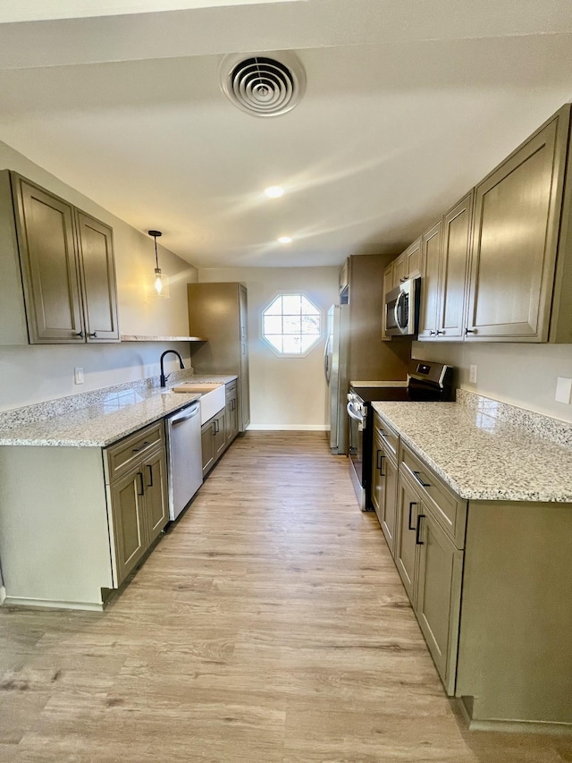 kitchen with sink, hanging light fixtures, light hardwood / wood-style flooring, appliances with stainless steel finishes, and light stone counters