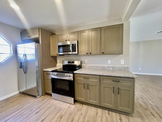 kitchen with light stone counters, stainless steel appliances, and light wood-type flooring