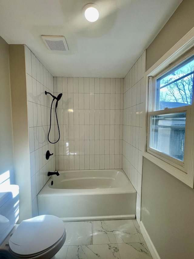 bathroom with tiled shower / bath combo and toilet