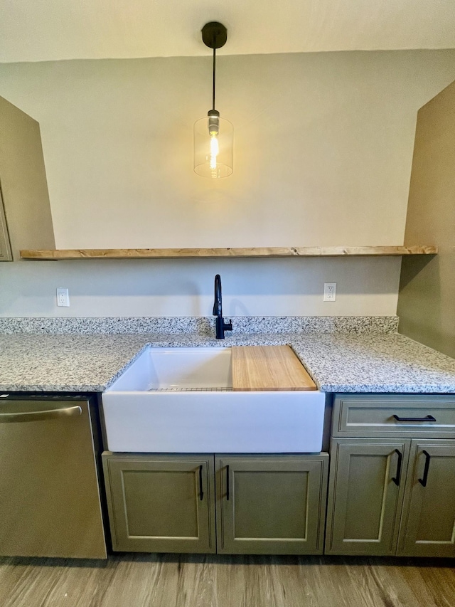 kitchen with light stone countertops, stainless steel dishwasher, sink, light hardwood / wood-style flooring, and hanging light fixtures