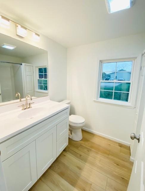 bathroom with walk in shower, vanity, toilet, and hardwood / wood-style floors