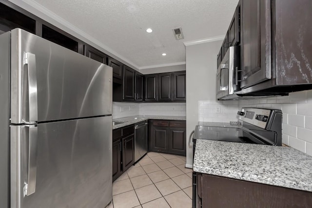 kitchen featuring tasteful backsplash, a textured ceiling, stainless steel appliances, crown molding, and light tile patterned floors