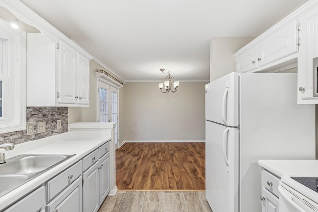 kitchen with tasteful backsplash, a chandelier, white cabinets, and light hardwood / wood-style floors