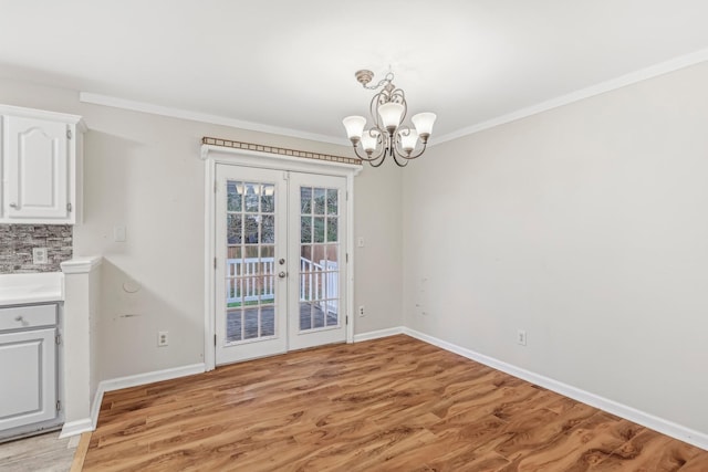 unfurnished dining area featuring a chandelier, french doors, light hardwood / wood-style floors, and ornamental molding