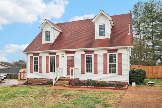 cape cod home with a storage shed and a front yard