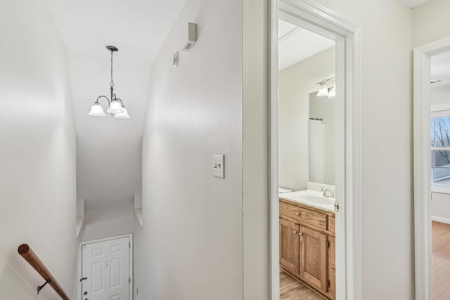 stairway featuring hardwood / wood-style flooring, sink, and an inviting chandelier