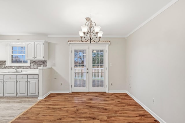 unfurnished dining area with french doors, an inviting chandelier, light hardwood / wood-style floors, and sink