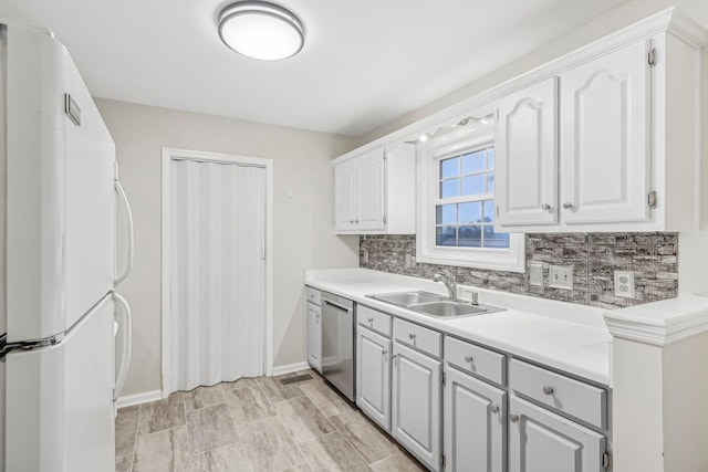 kitchen with white cabinets, sink, white fridge, and stainless steel dishwasher