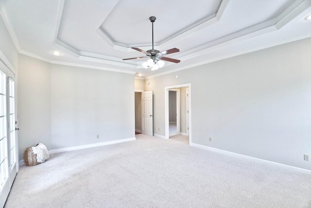 carpeted empty room featuring ceiling fan, a raised ceiling, and ornamental molding