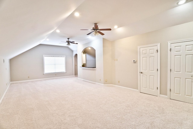 additional living space with ceiling fan, light colored carpet, and vaulted ceiling