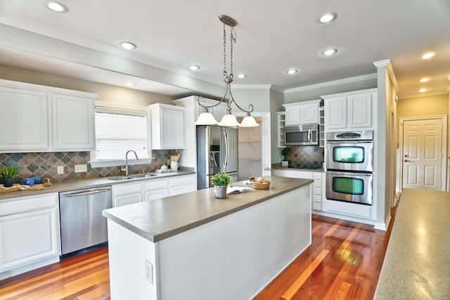 kitchen featuring sink, light hardwood / wood-style flooring, decorative light fixtures, a kitchen island, and appliances with stainless steel finishes