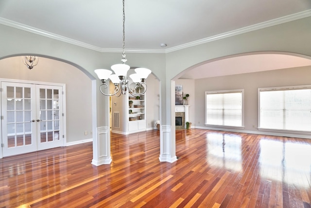 unfurnished dining area with hardwood / wood-style floors, ornamental molding, french doors, and a notable chandelier