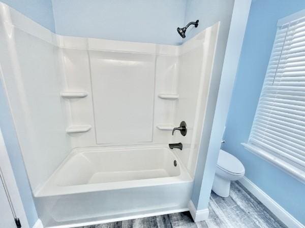 bathroom featuring shower / bathing tub combination, toilet, and wood-type flooring