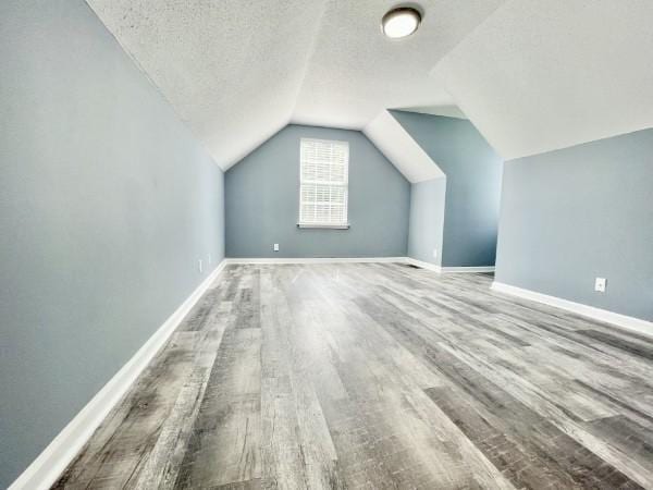 bonus room with wood-type flooring, a textured ceiling, and lofted ceiling