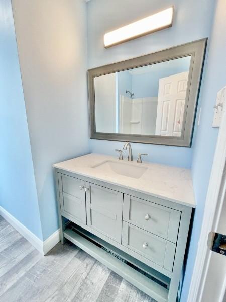 bathroom featuring a shower, vanity, and wood-type flooring