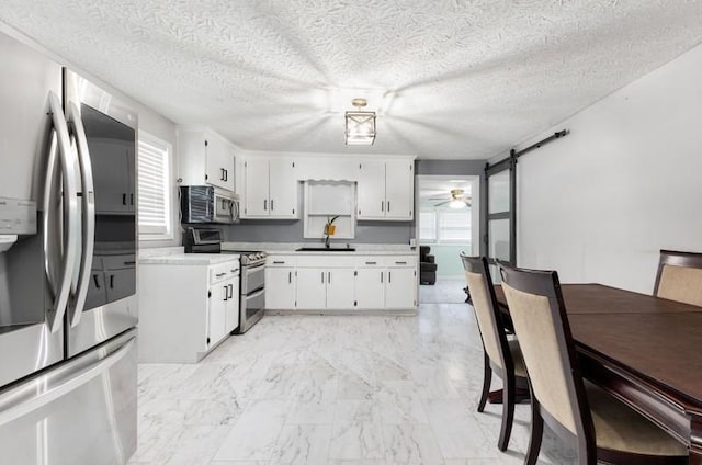 kitchen with white cabinets, a barn door, and appliances with stainless steel finishes