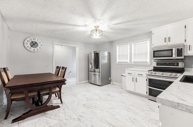 kitchen with a textured ceiling, stainless steel appliances, white cabinetry, and sink