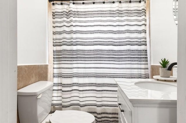 bathroom with curtained shower, vanity, and toilet