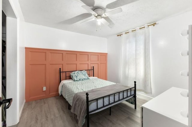 bedroom with ceiling fan, a textured ceiling, and light wood-type flooring