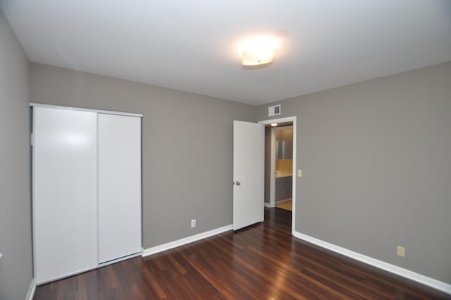 unfurnished bedroom with a closet and dark hardwood / wood-style flooring