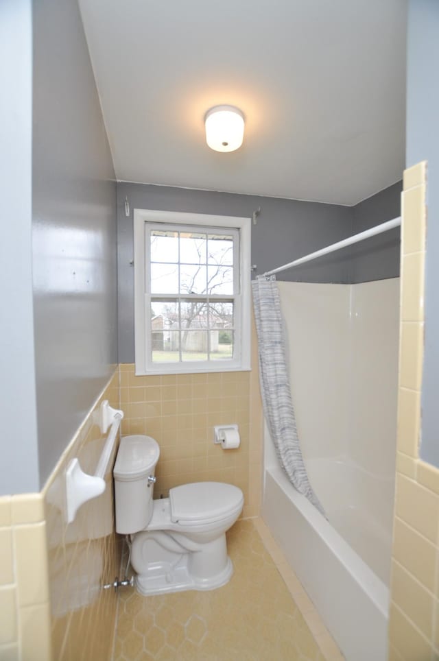 bathroom with tile patterned floors, shower / tub combo with curtain, tile walls, and toilet